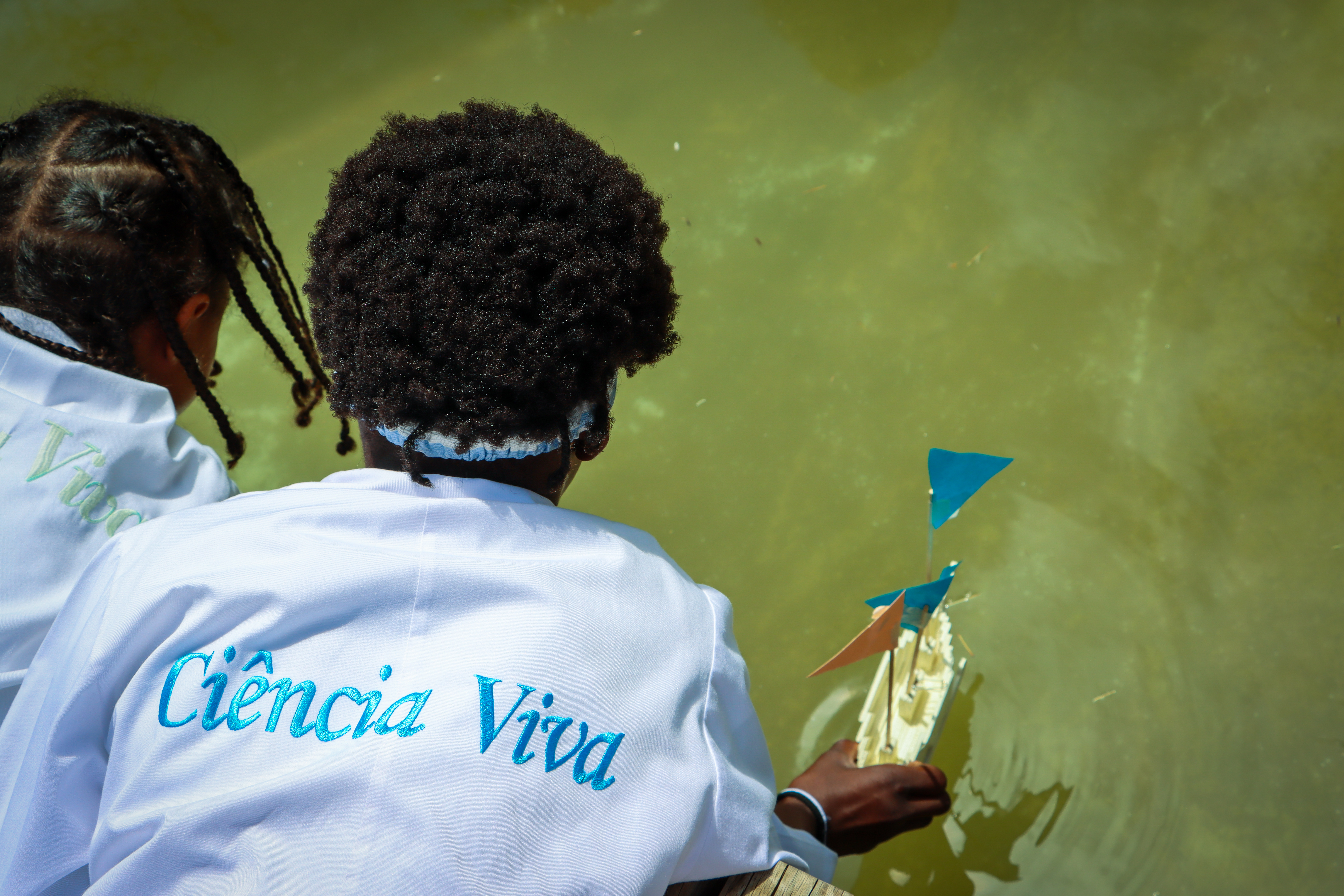 Students looking at a small boat in on the water